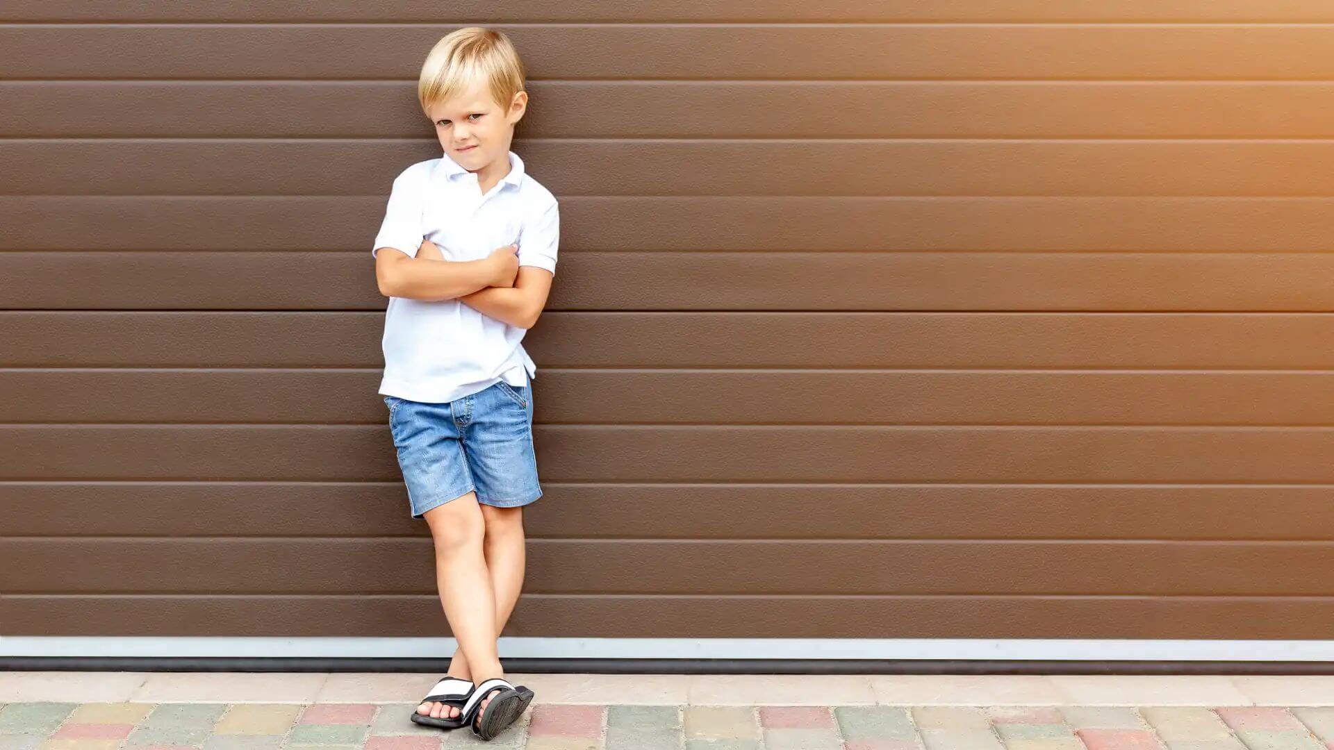 child standing against garage door - garage door safety concept