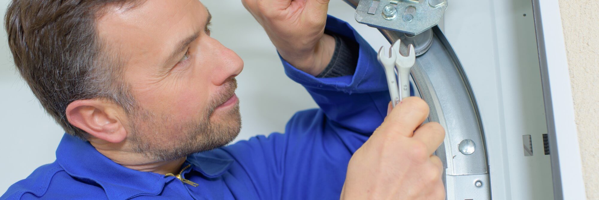 Common garage door issues - Close up of a man as he fixes a garage door